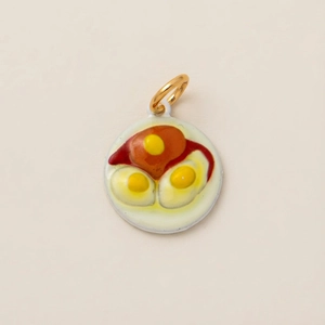 Macro shot of colorful enamel fried eggs and ham pendant with a polished gold jump ring