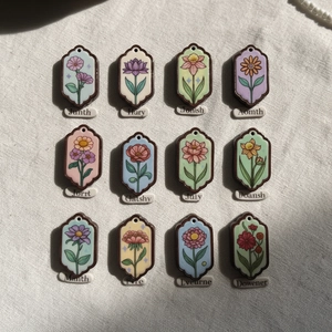 Set van 12 vintage 18K gouden bloemenhangers met Engelse labels op beige getextureerde stof