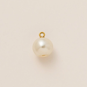 Élégant pendentif perle ronde avec bélière en métal doré sur fond beige minimaliste