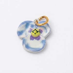 Détail d'un pendentif pensée en céramique bleue avec visage et anneau plaqué or