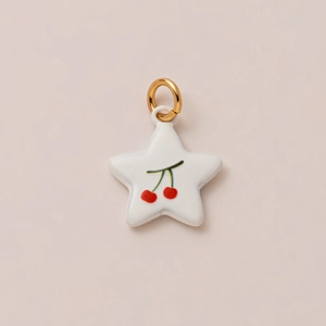 Detalle del colgante de cerámica en forma de estrella con motivo de cereza y aro dorado