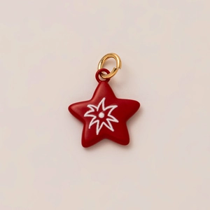 Primer plano de un colgante de estrella roja con rayos blancos y aro dorado para joyería DIY