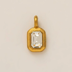 Close-up of emerald cut clear gemstone pendant with vintage gold metal frame and top loop