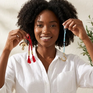 Woman holding colorful woven mushroom and horseshoe pendant keychains with gold accents