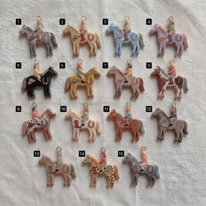 Collezione di 15 ciondoli a cavallo colorati con anelli placcati oro 18K su tessuto bianco
