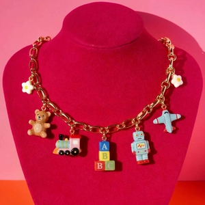 Gold chunky chain necklace with colorful toy pendants like a bear, train, and blocks