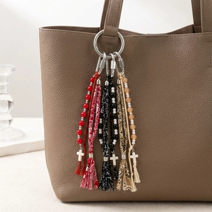 Ethnic style keychain set with bead tassels and cross charms hanging on a leather bag