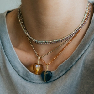 Kleurrijke gelaagde kralenketting met hartvormige stenen hangers gedragen door model