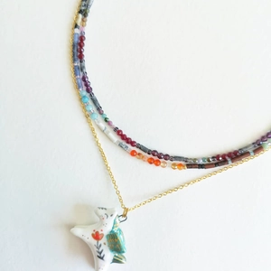 Macro detail of layered beaded necklace with hand-painted ceramic pony pendant