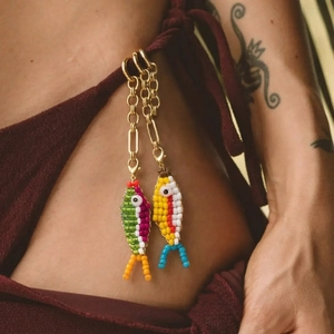 Bunte Fisch-Perlenanhänger an rotem Badeanzug für einen sommerlichen Strand-Look