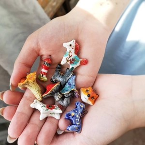 Macro detail of colorful animal and mushroom charms with 14K gold plated loops