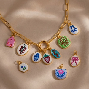 Artistieke gouden ketting met kleurrijke emaille bedeltjes in huis en bloemvorm