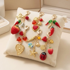 Golden strawberry and chili charms keychain set on velvet cushion display