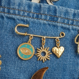 18K vergoldete Sicherheitsnadel-Brosche mit Evil Eye, Sonne und Herz-Anhängern auf Jeans