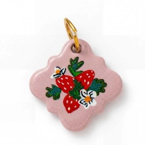 Dettaglio del ciondolo in ceramica rosa con motivo fragola e anello dorato per DIY