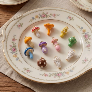 Colorful mushroom pendants with pearls for DIY jewelry making on a vintage floral plate