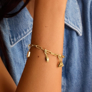 Detailaufnahme des goldenen Büroklammer-Armbands mit Herz- und Rugbyball-Anhängern
