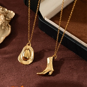 Detail shot of golden cowboy hat and boot pendants hanging on a black jewelry box