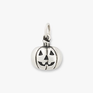 Macro detail of a vintage titanium pumpkin charm with oxidized Jack-o'-lantern features