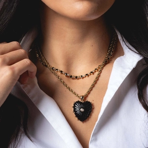 Gros plan sur le collier double épaisseur avec pendentif cœur noir et chaîne dorée