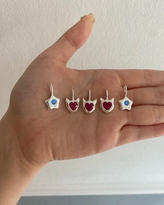 Close-up of star and heart pendants with colorful zircon inlays on person's hand