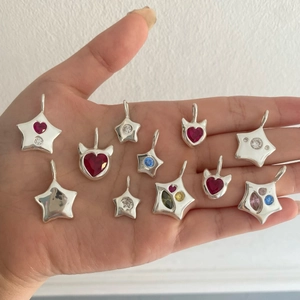 Vintage heart and star pendants with colorful zircons on palm for size reference