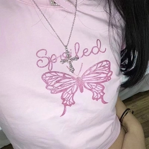 Close-up of rhinestone cross necklace paired with a pink Y2K butterfly graphic tee