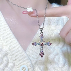 Detailed close-up of a Gothic cross necklace with colorful zircons and a small white bow
