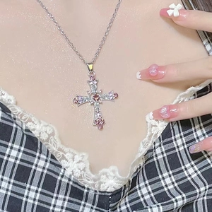 Detail of cross pendant necklace with pink and clear zircons in Y2K gothic style