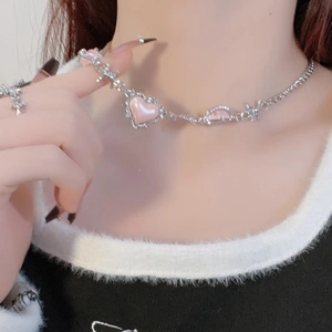 Close-up of pink heart pendant with silver thorn chain design on a fashion model