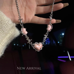 Close-up of silver thorn necklace with pink heart charms in a trendy lifestyle setting