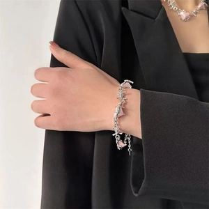 Macro detail of silver barbed wire bracelet with pink heart gemstone on black suit background