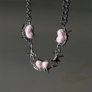 Detailed macro of pink heart pendants with silver thorn design on a link chain