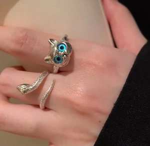 Close-up of vintage silver cat ring with blue eyes and snake wrap ring on finger