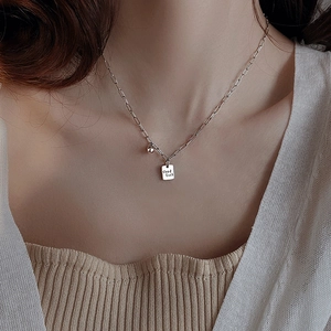 Collar minimalista con colgante cuadrado Good Luck y cadena de clips usado por una modelo