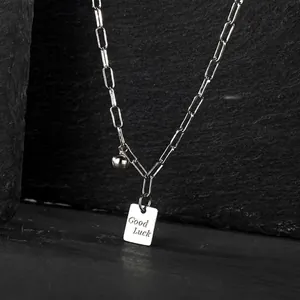 Detalle del collar con colgante cuadrado plateado Good Luck y cadena de acero minimalista