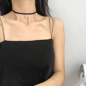 Dettaglio del choker in velluto nero con ciondolo a perla bianca indossato da una modella
