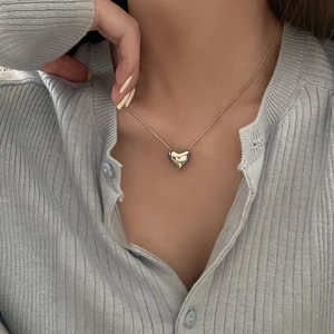 Elegant gold heart pendant necklace on snake bone chain worn by model with blue sweater
