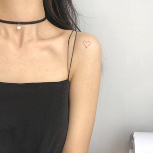 Adesivo tatuaggio cuore rosso minimalista sulla spalla con girocollo di perle