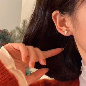 Detailed view of a cute reindeer Christmas earring with golden finish and white enamel