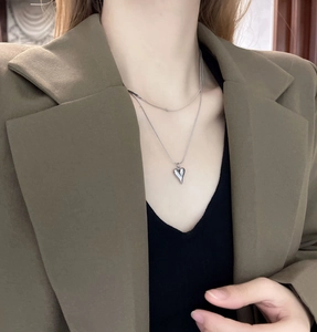 Close-up of double-layered silver steel necklace with polished heart pendant and snake chain