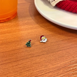 Macro view of Christmas tree and Santa earrings with colorful enamel finish on wood