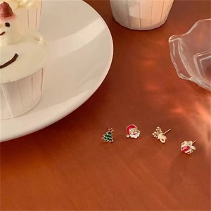 Close-up of a 4-piece Christmas earring set with reindeer and Santa on a festive wooden surface