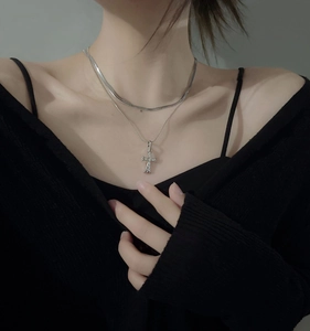 Detail of silver layered snake chain necklace with sparkling zircon cross pendant on model