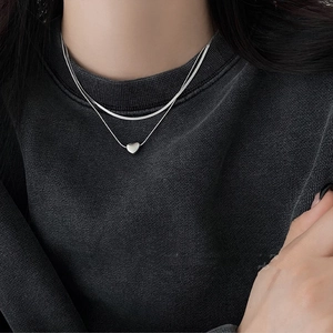 Double-layered stainless steel snake chain with heart pendant on grey sweater