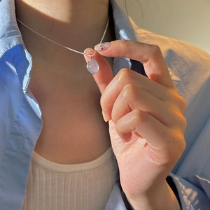 Detail of moonstone pendant necklace showing the silver chain and blue gemstone on a woman