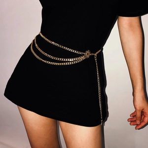 Detail of layered gold metal waist chain with sun flower buckle on a black dress