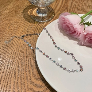 Collier à fleurs colorées sur une assiette blanche avec roses roses et décor de thé