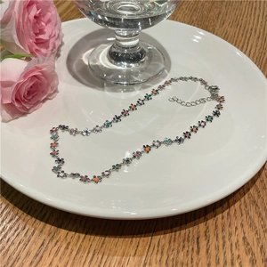 Détail du collier de fleurs colorées en émail avec fermoir mousqueton argenté sur assiette