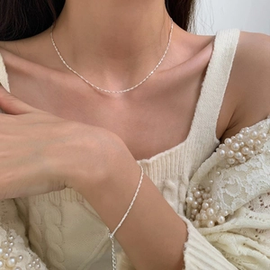 Conjunto minimalista de collar y pulsera de cadena trenzada de plata usado por una modelo